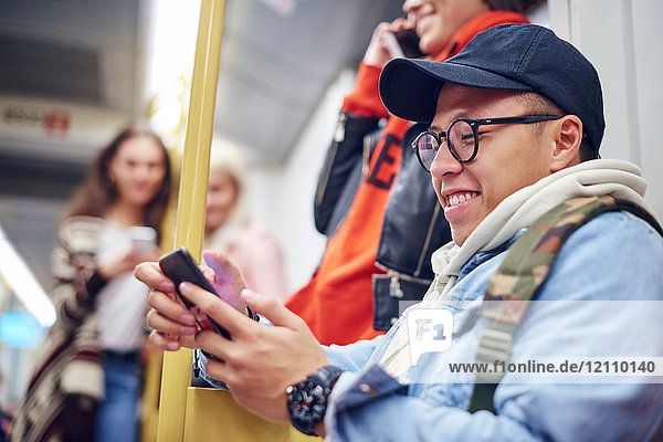 Young man looking at smartphone on city tram