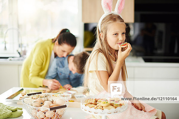 Mädchen isst Osterkekse auf der Küchentheke
