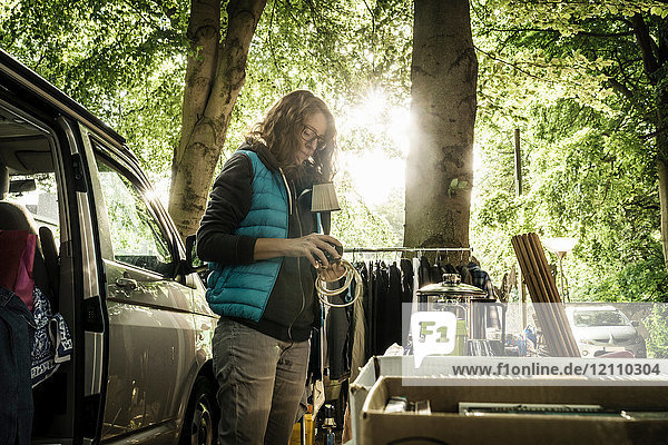 Frau  die am Stand auf dem Waldflohmarkt eine Lampe aus zweiter Hand auspackt