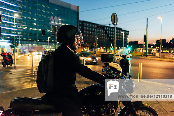 Reifer Geschäftsmann nachts im Freien  Motorrad fahren