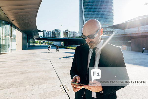 Reifer Geschäftsmann im Freien  der ein Smartphone benutzt
