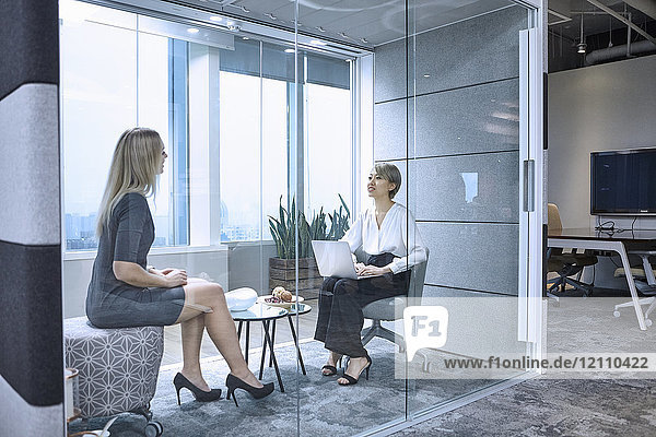 Colleagues having meeting in glass pod in office