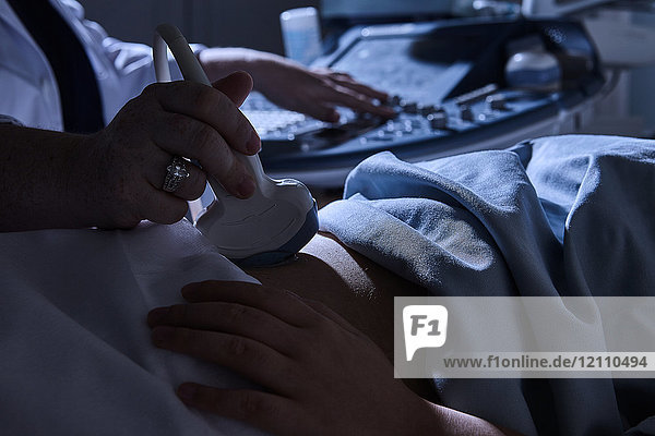 Schrägansicht der Ultraschalluntersuchung einer schwangeren Patientin durch den Sonographen