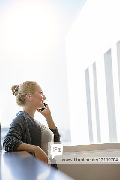 Young businesswoman making smartphone call in office corridor