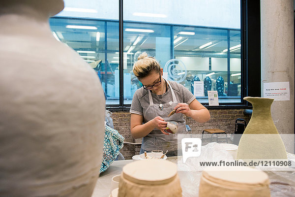Frau in Kunstatelier Töpferware glasierend
