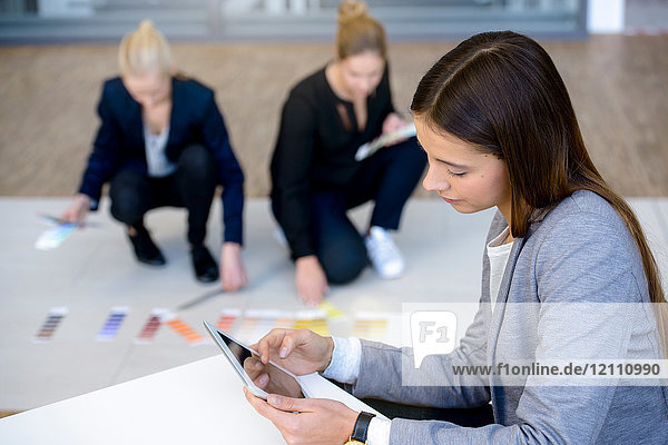 Junge Geschäftsfrau im Büro betrachtet digitales Tablet