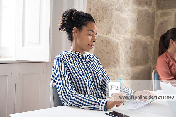 Geschäftsfrau liest Papierkram am Büroschreibtisch