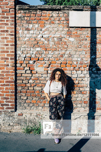Frau posiert gegen Ziegelmauer
