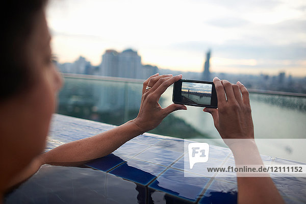 Frau im Infinity-Pool beim Fotografieren der Ansicht mit dem Smartphone  Bangkok  Krung Thep  Thailand  Asien