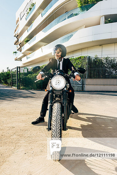 Porträt eines reifen Geschäftsmannes im Freien  auf Motorrad sitzend  Motorradhelm tragend