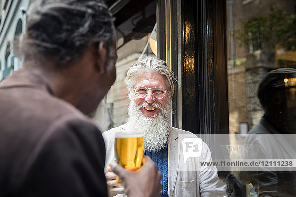 Zwei reife Männer  die vor der Kneipe stehen und Bier trinken