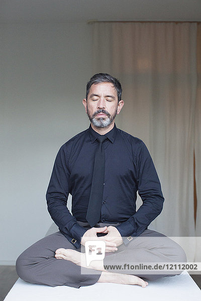 Mature businessman meditating at home