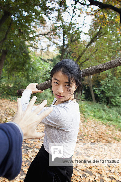 Aggressive Frau hält Stock vor der Hand im Park