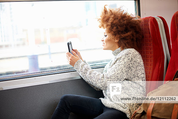 Frau  die mit dem Mobiltelefon aus dem Zug fotografiert  London