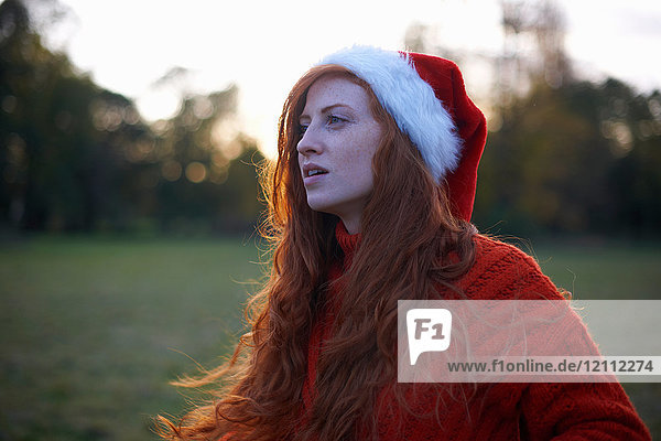 Junge Frau in ländlicher Umgebung  mit Weihnachtsmannhut