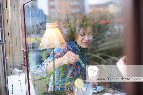 Blick durch das Fenster einer Frau im Kaffeehaus  die eine heiße Schokolade genießt