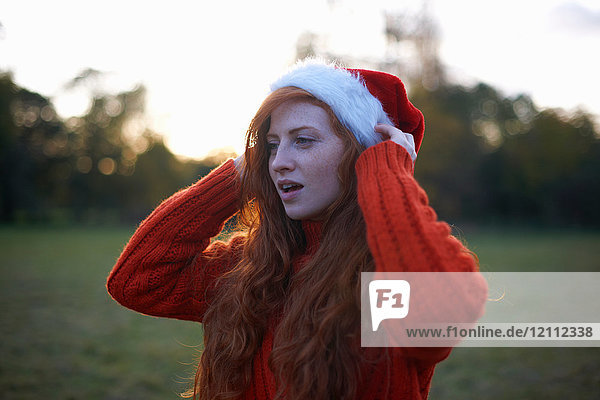 Junge Frau in ländlicher Umgebung  mit Weihnachtsmannhut
