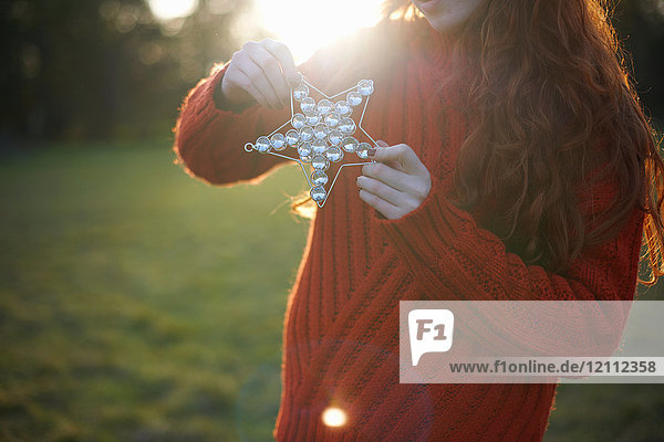 Young woman in rural setting  holding Christmas star  mid section