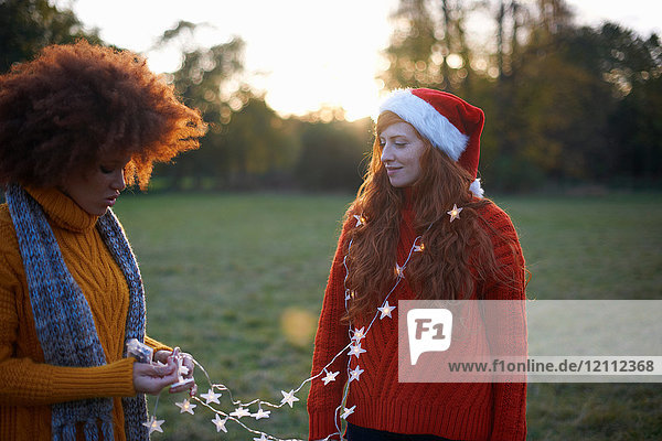 Two young women  in rural setting  young woman wrapped in fairy lights