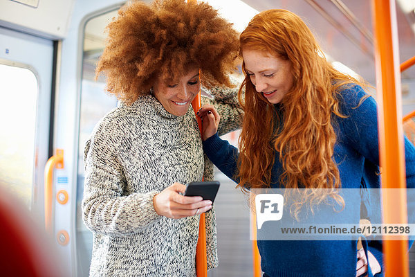 Freunde tauschen Botschaften auf Mobiltelefonen im Zug aus  London