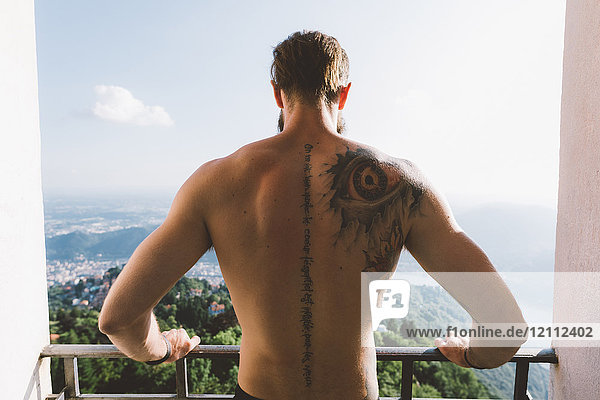 Tattooed young man looking down from viewing platform  Lake Como  Lombardy  Italy