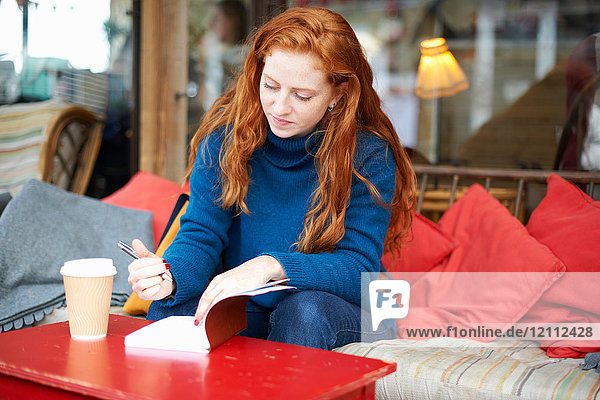 Woman at coffee shop writing in notepad