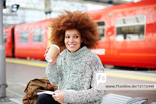 Woman on bench on train station platform  London