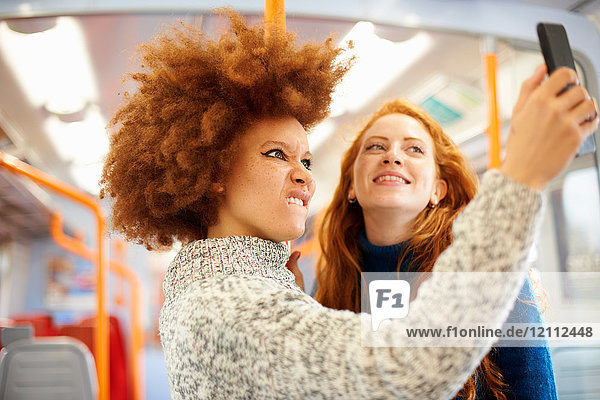 Friends taking selfie with mobile phone on train  London