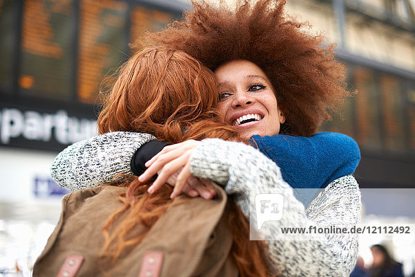 Two young women hugging at train station