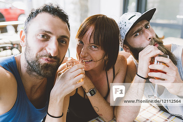 Portrait of three young hipster friends drinking cocktails