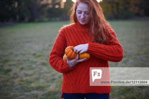 Young woman in rural setting  holding pumpkins