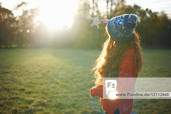 Young woman in rural setting  holding star up towards sunlight