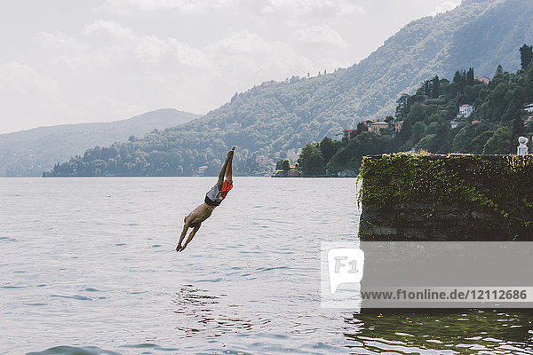 Junge männliche Schwimmer tauchen vom Pier  Comer See  Lombardei  Italien