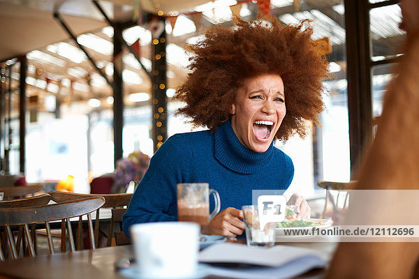 Woman dining in cafe with friend  laughing