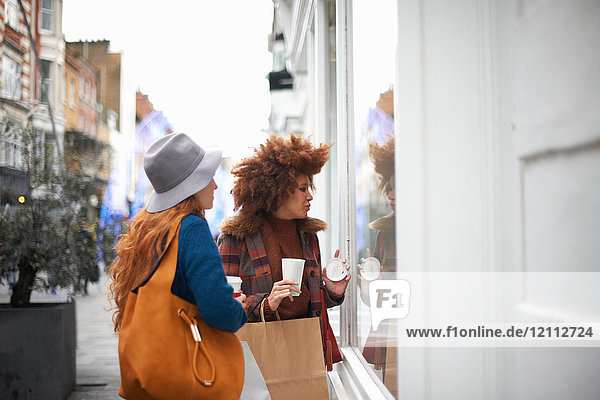 Two young women looking in shop window