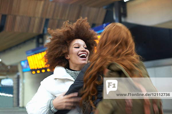 Two young women greeting each other at train station