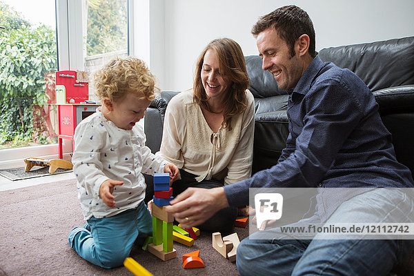 Eltern und Kleinkind spielen mit Bausteinen