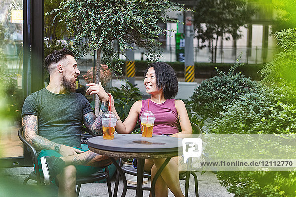 Ein multiethnisches Hipster-Paar unterhält sich in einem Straßencafé  Shanghai Französische Konzession  Shanghai  China