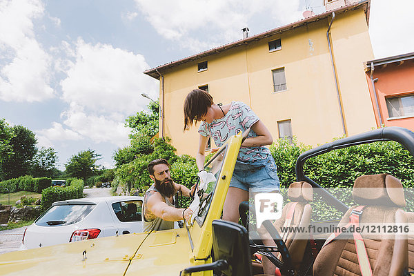 Young couple on road trip cleaning windscreen  Como  Lombardy  Italy