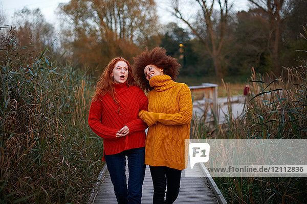 Two young women  walking arm in arm along rural pathway