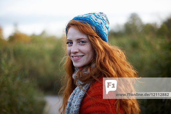 Portrait of red haired woman looking over shoulder at camera smiling