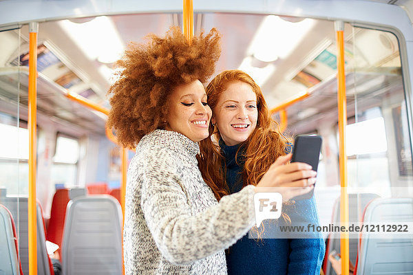 Friends taking selfie with mobile phone on train  London