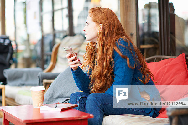 Frau im Café mit Mobiltelefon