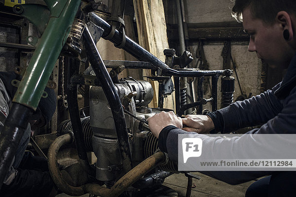 Mechanic repairing vintage motorcycle engine in workshop