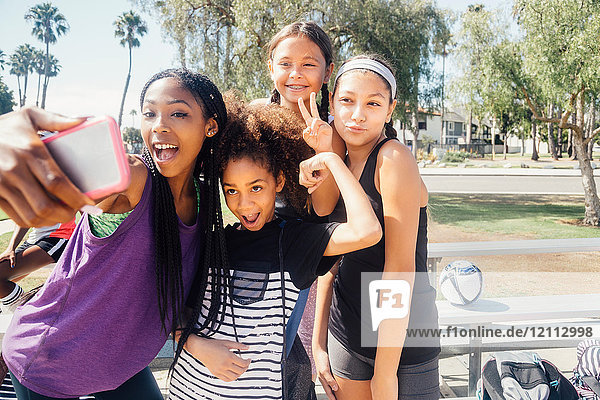 Schülerinnen-Fussballspielerinnen mit Smartphone-Selfie auf dem Schulsportplatz