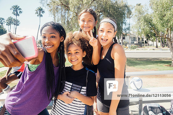 Schülerinnen-Fussballspielerinnen mit Smartphone-Selfie auf dem Schulsportplatz