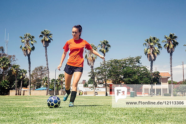 Teenager-Schülerin kickt Fussball auf Schulsportplatz