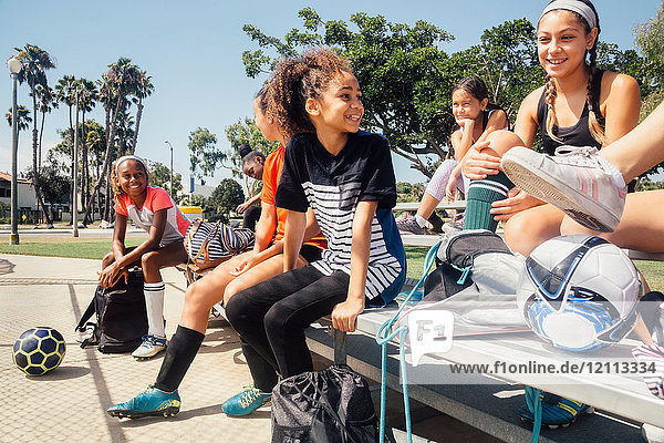 Schülerinnen-Fussballspielerinnen unterhalten sich auf der Sportplatzbank der Schule