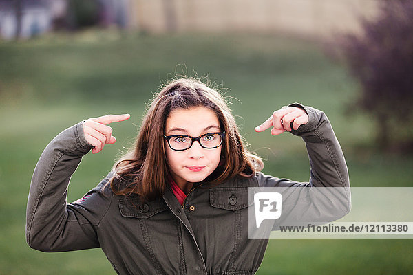 Portrait of girl in spectacles pointing at her face