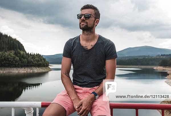 Mann sitzt auf Sicherheitsbarriere am See  Koralat  Zagrebacka  Kroatien